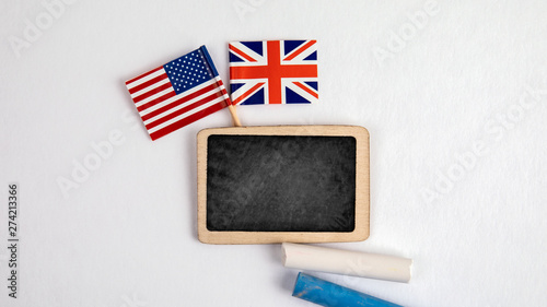 British and United States Of America flags. Small whiteboard with chalk. Top view on a white background. Mockup, copy space. photo