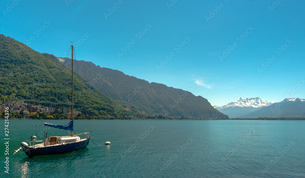 sailboat on the shores of Lake Geneva with great view of the Swiss Alps behind as seen from the Montreux Riviera