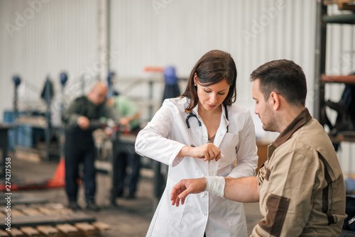 Beautiful female doctor examining factory worker.