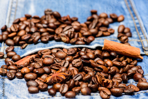 Fresh roasted coffee close up. Beans and spices in jeans pocket. Coffee for inspiration and energy charge. Coffee shop or store. Degree of roasting coffee beans. Texture and background concept