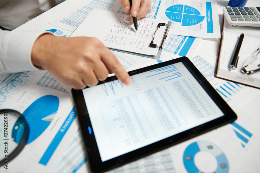 Businessman working and calculating, reads and writes reports. Using tablet pc. Office employee, table closeup. Business financial accounting concept. Businessman working and calculating, reads and writes reports. Using tablet pc. Office employee, table closeup. Business financial accounting concept.