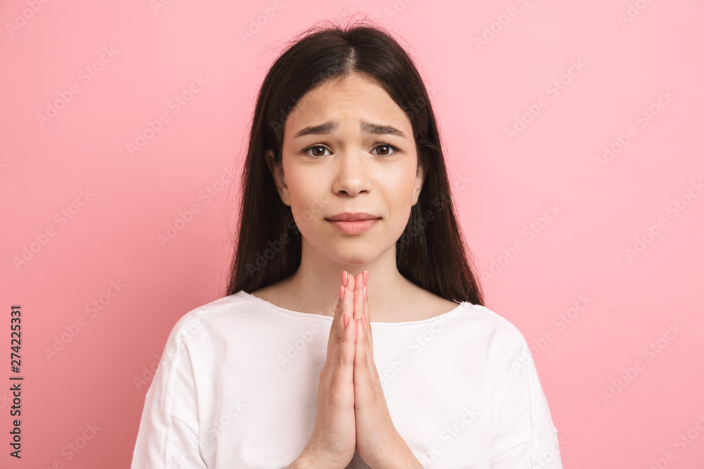 Portrait closeup of young european girl looking at camera and praying with palms together Portrait closeup of young european girl looking at camera and praying with palms together