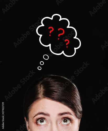 A girl on a black background looks at the cloud with a question mark