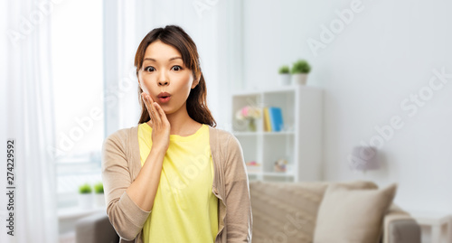 emotion  expression and people concept - surprised asian woman over home room background