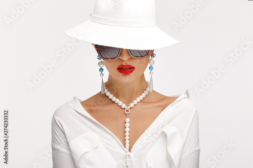 Beautiful girl in an elegant white hat, sunglassess and exquisite jewelry. photo