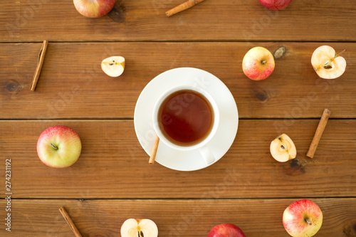 objects and drinks concept - cup of black tea with apples and cinnamon on wooden table
