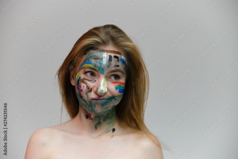 Naklejka premium Concept art photo portrait of a beautiful smiling girl woman with red hair with a pattern on her face on a light gray background. Shows emotions. Made in a studio.