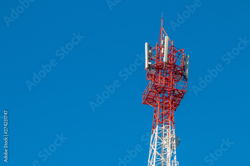 Wireless Communication Antenna Transmitter. Telecommunication tower with antennas on blue sky background.
