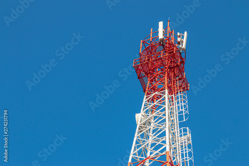 Wireless Communication Antenna Transmitter. Telecommunication tower with antennas on blue sky background.