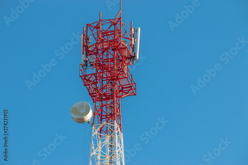 Wireless Communication Antenna Transmitter. Telecommunication tower with antennas on blue sky background.