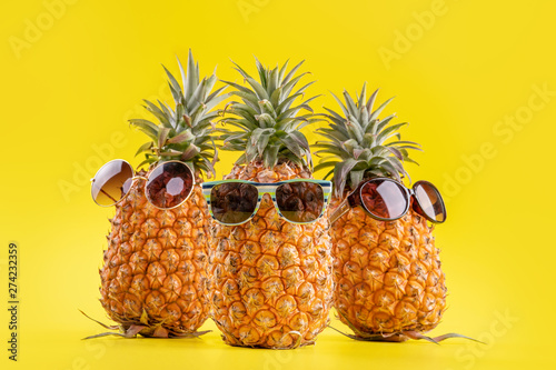 Creative pineapples with sunglasses isolated on yellow background  summer vacation beach idea design pattern  copy space  close up  blank for text