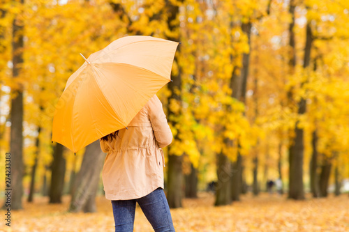season  rainy weather and people concept - young woman with umbrella in autumn park