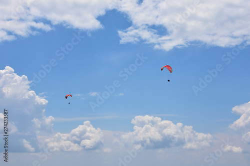 Two ram-air red tandem paragliders flying high in the blue sky with white cirrous clouds photo