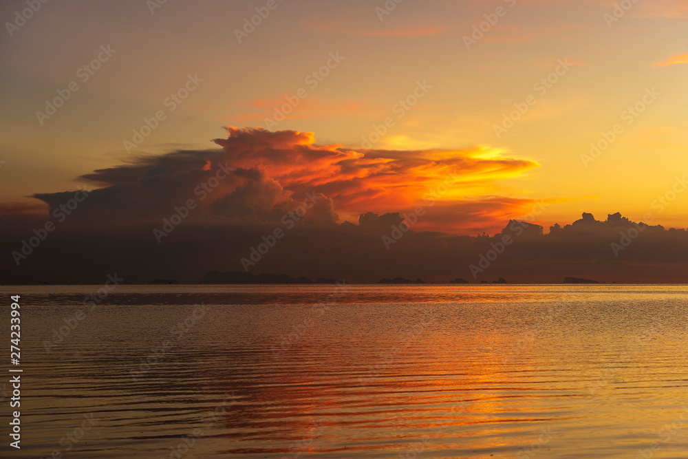 Storm clouds during sunset.Colorful sunset over calm sea water near tropical beach. Summer vacation concept. Island Phangan, Thailand