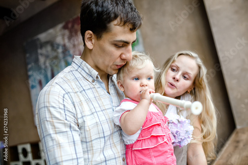 Tender family hugs. Mom, dad and daughter enjoy each other, girl playing a pipe photo