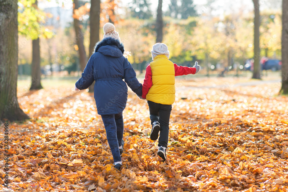 childhood, season and family concept - happy children running at autumn park childhood, season and family concept - happy children running at autumn park