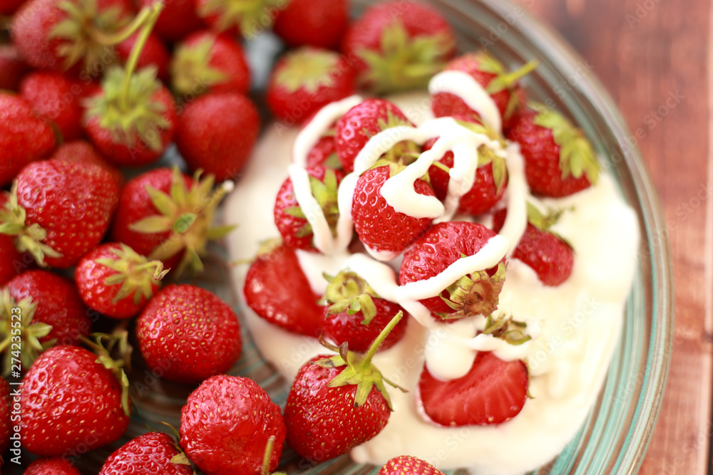 ripe, juicy strawberries with cream in a plate on a wooden table ripe, juicy strawberries with cream in a plate on a wooden table