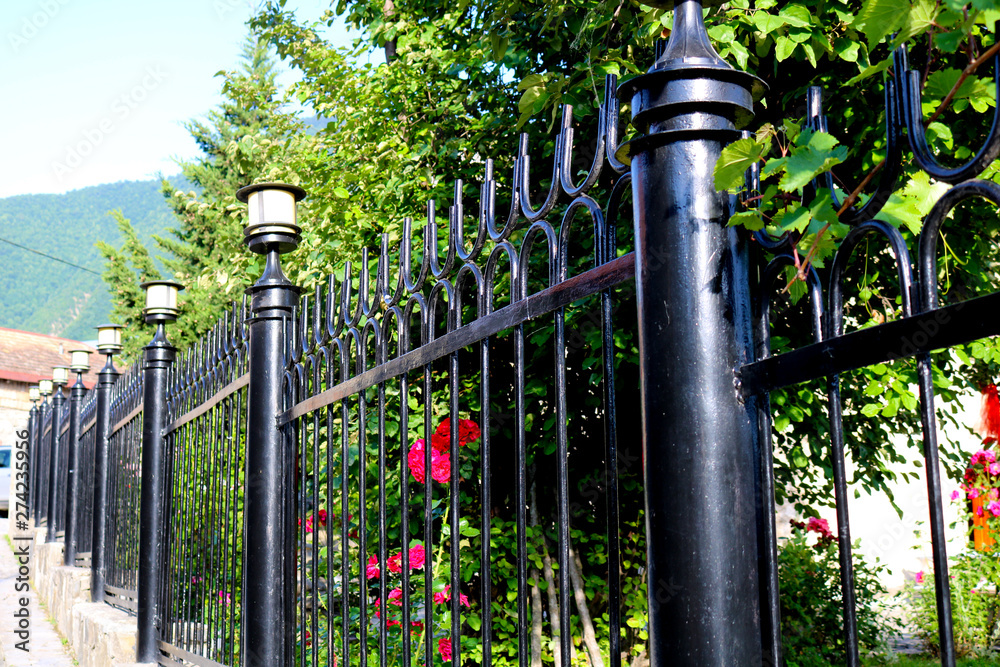 Garden fence made of iron in black. Wrought iron tracery black fence fragment Garden fence made of iron in black. Wrought iron tracery black fence fragment