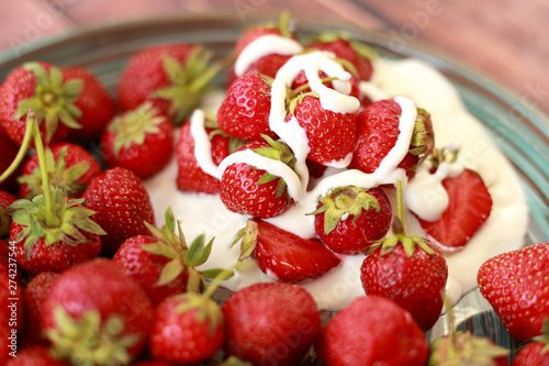 ripe, juicy strawberries with cream in a plate on a wooden table