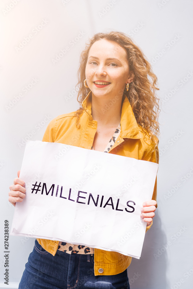 Young millennial teenage with red hair and a funny expression ,making lips and making a wink, holds a sign with the text Young millennial teenage with red hair and a funny expression ,making lips and making a wink, holds a sign with the text