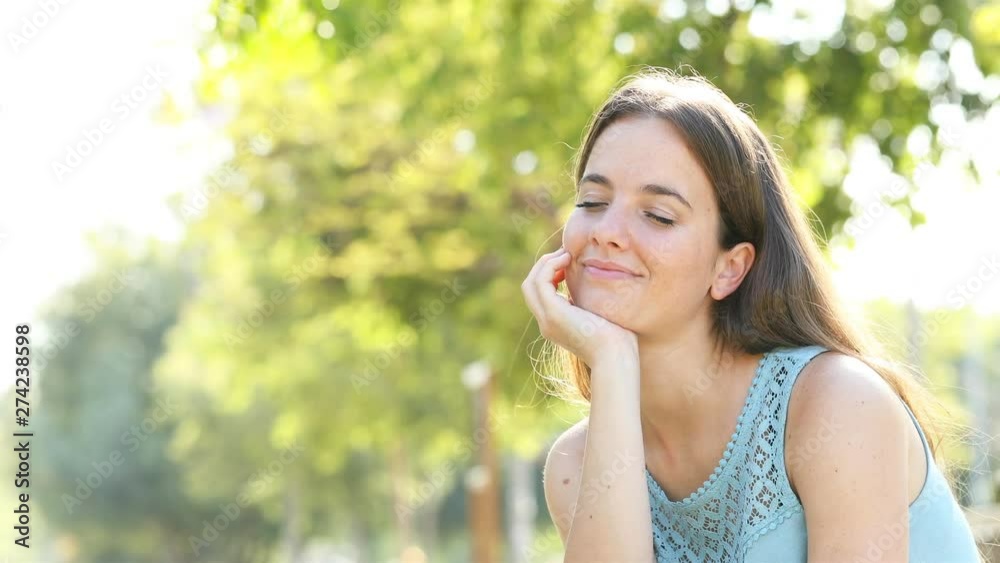 Happy woman relaxing in a park with a green background Happy woman relaxing in a park with a green background