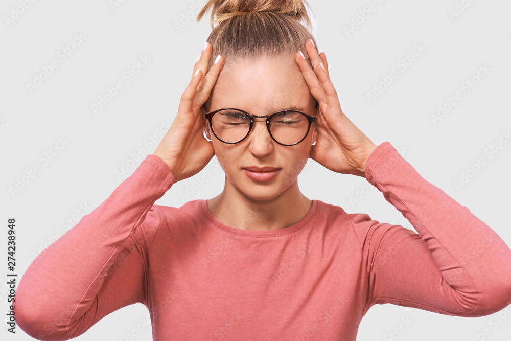 Close up portrait of stressed young woman having pain, discomfort, posing over white background. Pretty business woman suffering from headache and migraine. People and health concept