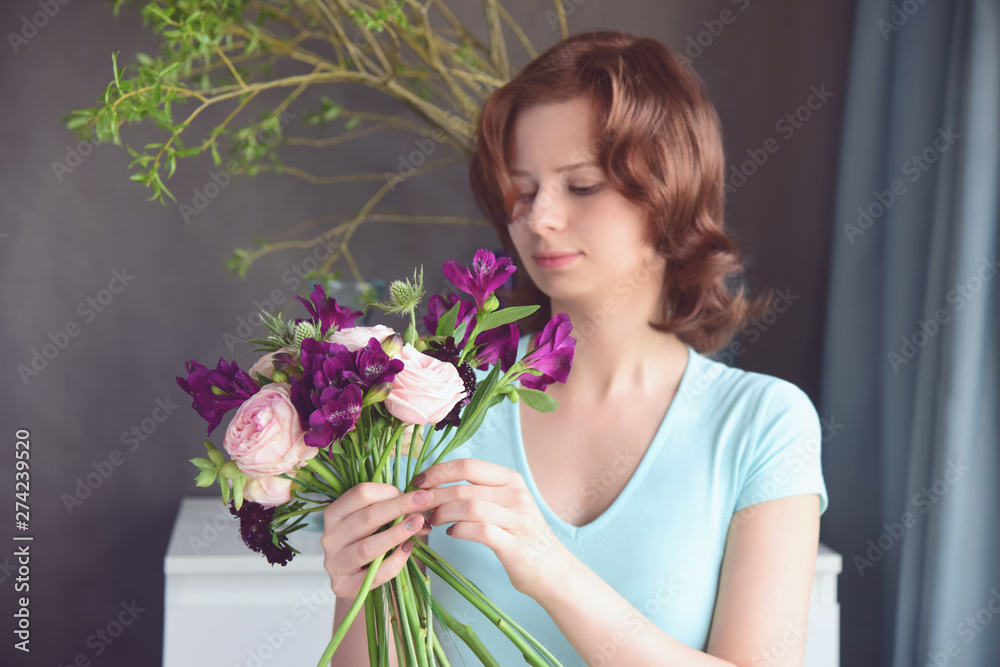 Red-haired girl florist makes an unusual bouquet of peony roses, succulents, alstroemeria,scabiosa and thistle. Floral workshop. Selective focus on the flowers, the girl's figure is blurred. Red-haired girl florist makes an unusual bouquet of peony roses, succulents, alstroemeria,scabiosa and thistle. Floral workshop. Selective focus on the flowers, the girl's figure is blurred.