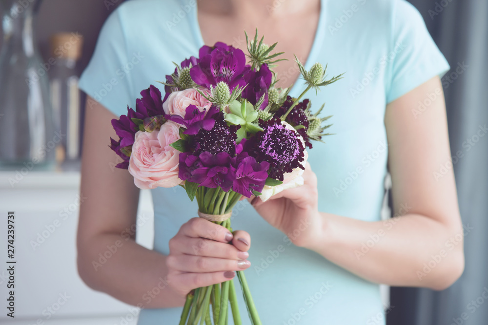 Florist girl completes an unusual bridal bouquet of peony roses, alstromeria, thistles and succulents. Female hands hold flowers close up..