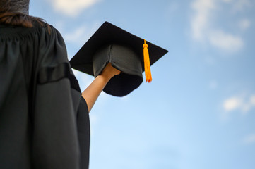 Long haired female students wearing black ruffle dresses expressing joy on graduation at the university.