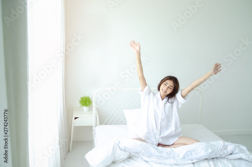 Asian women Smiled on the white futon in her bedroom.Beautiful woman smiling.Do not focus on the main object of this image.