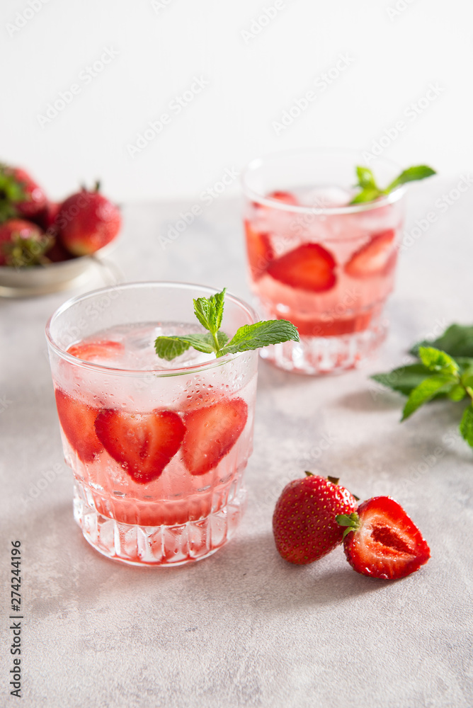 Fresh lemonade with ice, mint and strawberry in glasses on white table background. Cold refreshing summer drink. Sparkling glasses with berry cocktail. Fresh lemonade with ice, mint and strawberry in glasses on white table background. Cold refreshing summer drink. Sparkling glasses with berry cocktail.