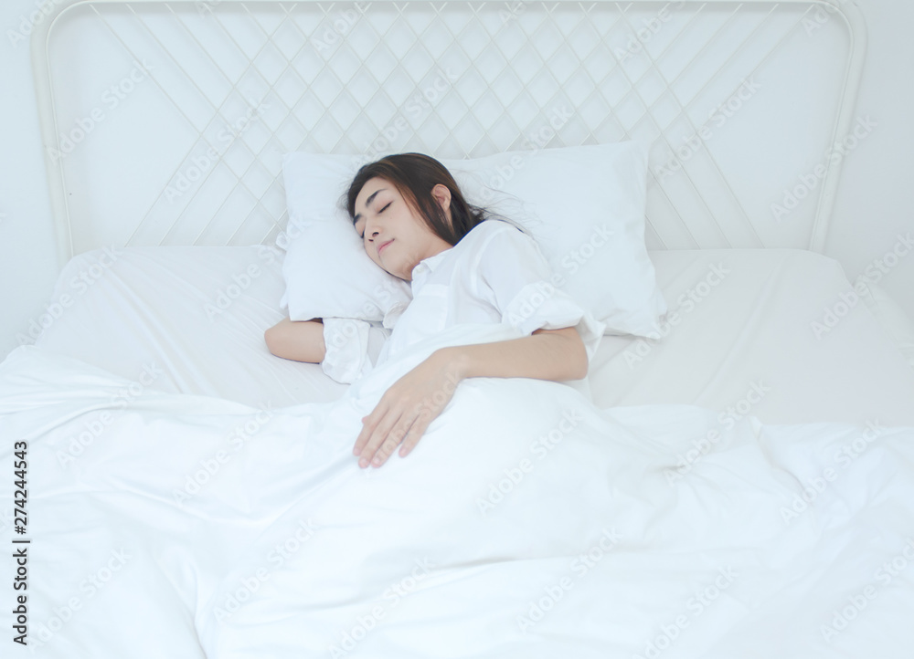 Asian women wear white pajamas in the bedroom. She has pain in the neck area.Do not focus on the main object of this image. Asian women wear white pajamas in the bedroom. She has pain in the neck area.Do not focus on the main object of this image.