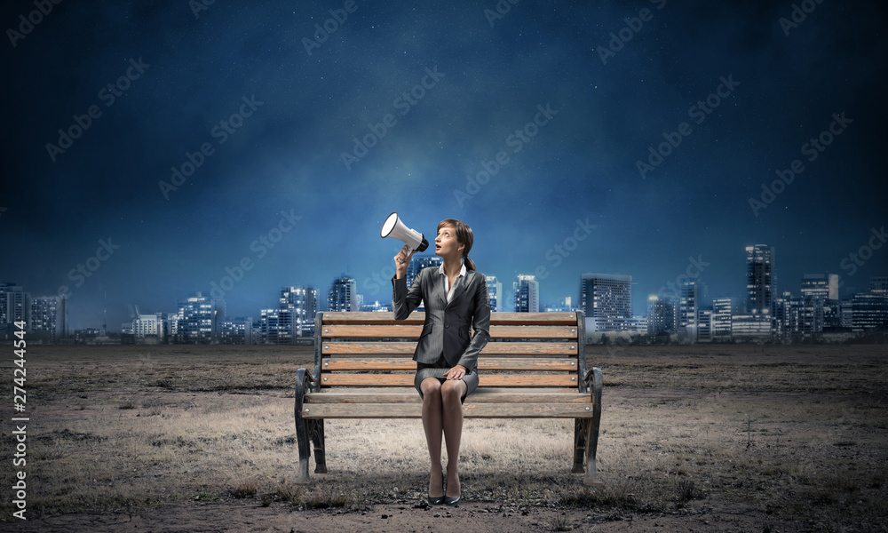 Business woman with megaphone on wooden bench Business woman with megaphone on wooden bench