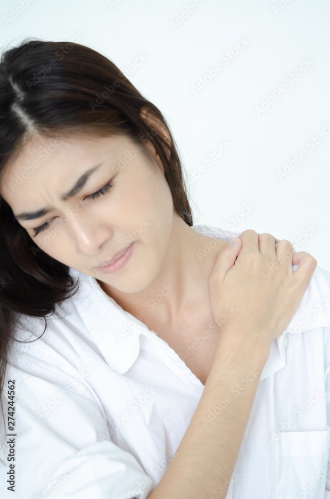 Asian women wear white pajamas in the bedroom. She has pain in the neck area. Asian women wear white pajamas in the bedroom. She has pain in the neck area.