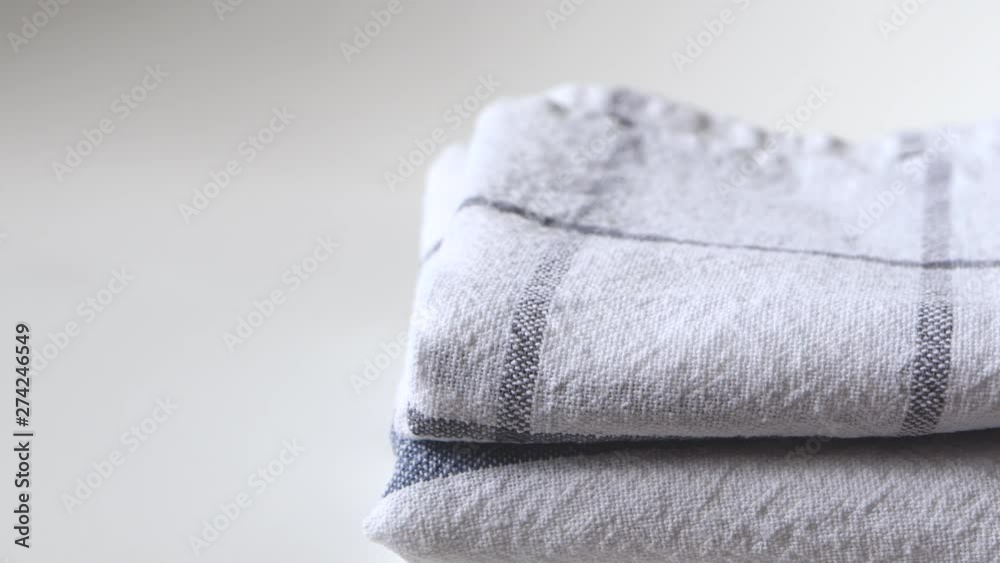 Hand takes kitchen towels from stack folded on white background with copy space