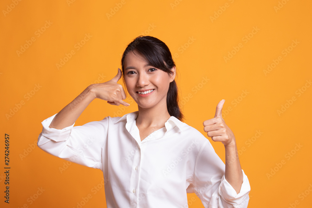 Young Asian woman thumbs up show with phone gesture. Young Asian woman thumbs up show with phone gesture.
