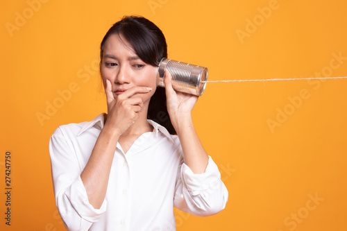 Young Asian woman hearing with tin can phone and thinking.