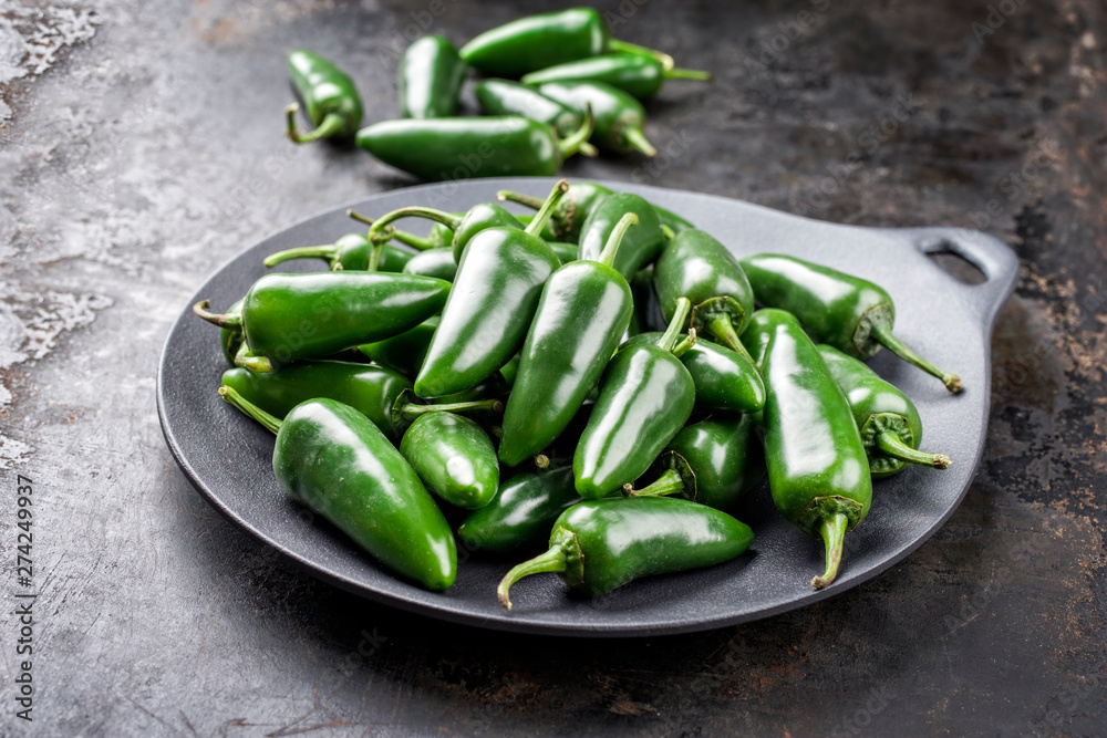 Fresh raw green hot jalapeno chili as closeup on a bowl with copy space Fresh raw green hot jalapeno chili as closeup on a bowl with copy space