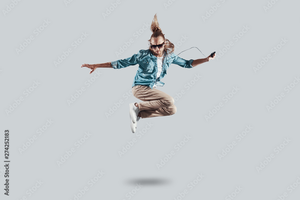 So cool! Full length of handsome young man hovering against grey background