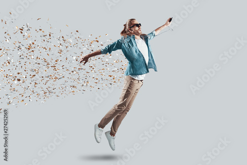 Foto Wow! Full length of handsome young man making a face while hovering against grey