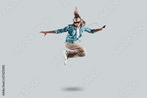 So cool! Full length of handsome young man hovering against grey background © G-Stock Faces