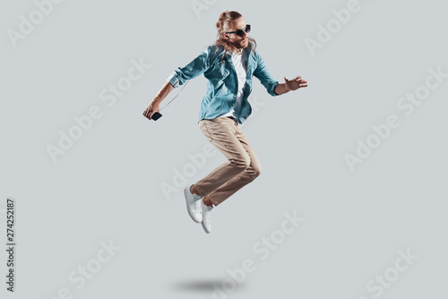 Fly! Full length of handsome young man hovering against grey background