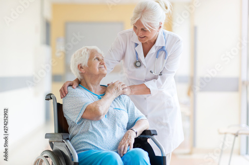 Senior woman in wheelchair with doctor in hospital © pikselstock