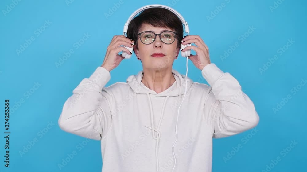 Love for music concept. Mature Woman Streams Music in Headphones on a blue background Love for music concept. Mature Woman Streams Music in Headphones on a blue background