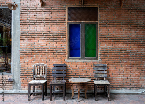 Antique set of wooden table and chairs with the classic color glass window on the old brick wall interior vintage style © pomphotothailand