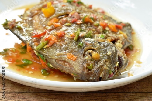 deep fried white pomfret dressing spicy sauce on plate