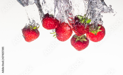 Close-up photo  on a very short exposure  strawberries falling into the water on a white background close up