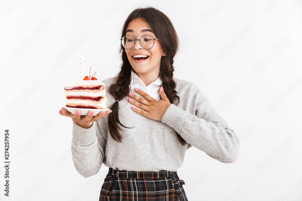 Photo closeup of happy teenage girl wearing eyeglasses smiling while holding big slice of birthday cake Photo closeup of happy teenage girl wearing eyeglasses smiling while holding big slice of birthday cake