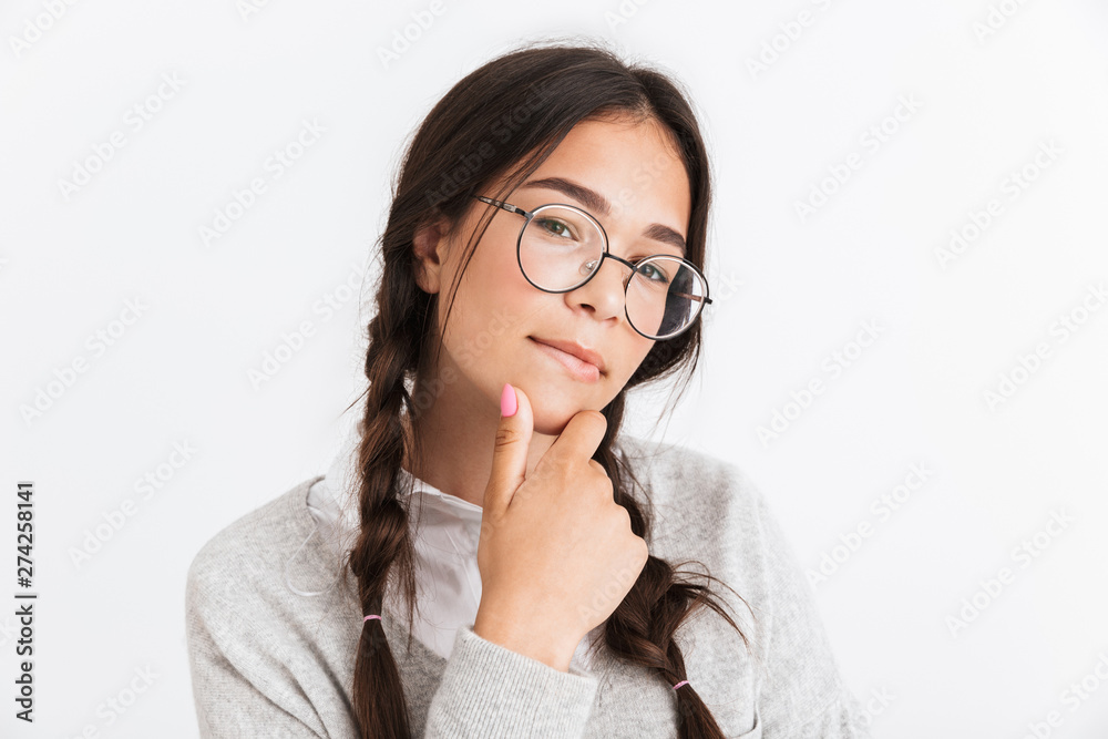 Photo closeup of thoughtful teenage girl wearing eyeglasses touching her chin and looking at camera Photo closeup of thoughtful teenage girl wearing eyeglasses touching her chin and looking at camera