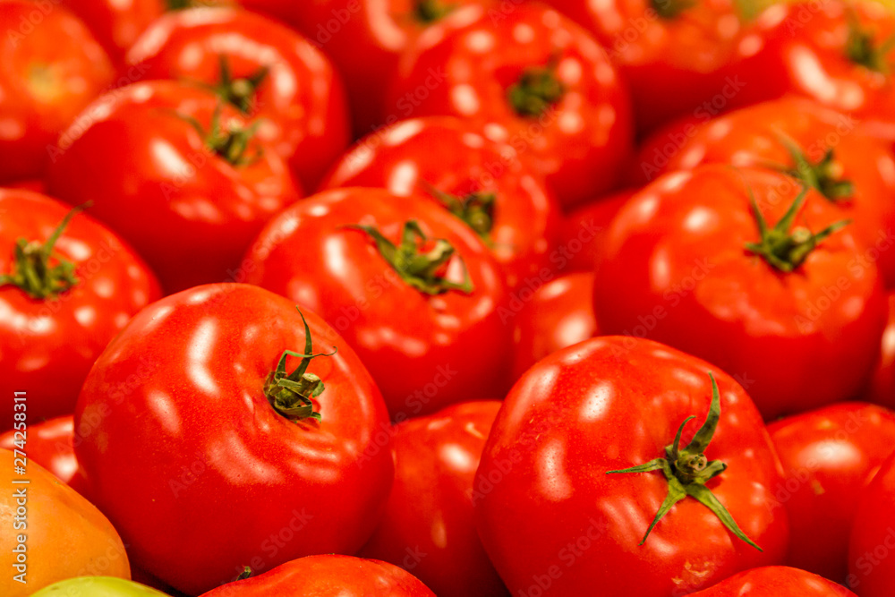 Bright red tomatoes on display at a farmers market stall Bright red tomatoes on display at a farmers market stall